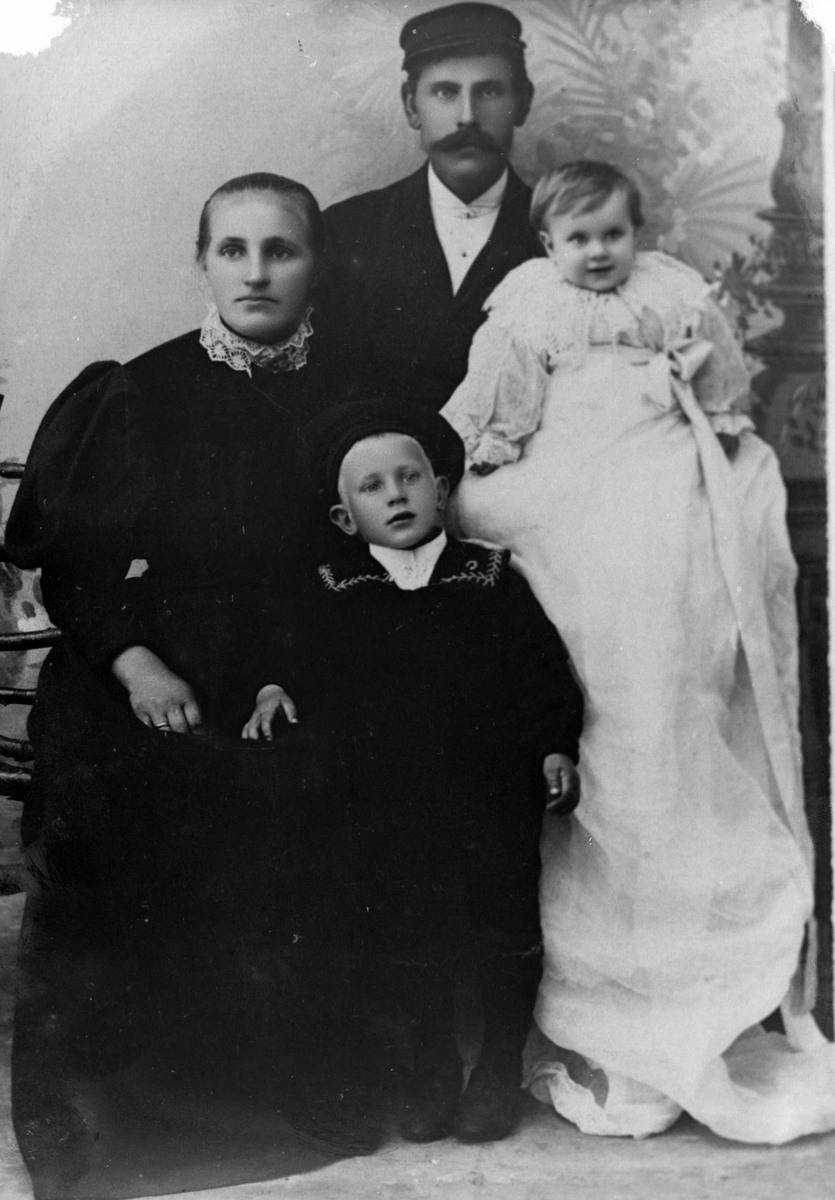 Studioportrett av en mann og kvinne med to barn, en av dem i dåpskjole.