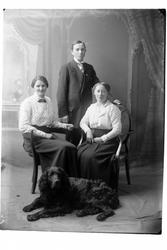 Studioportrett av tre personer med en hund.
