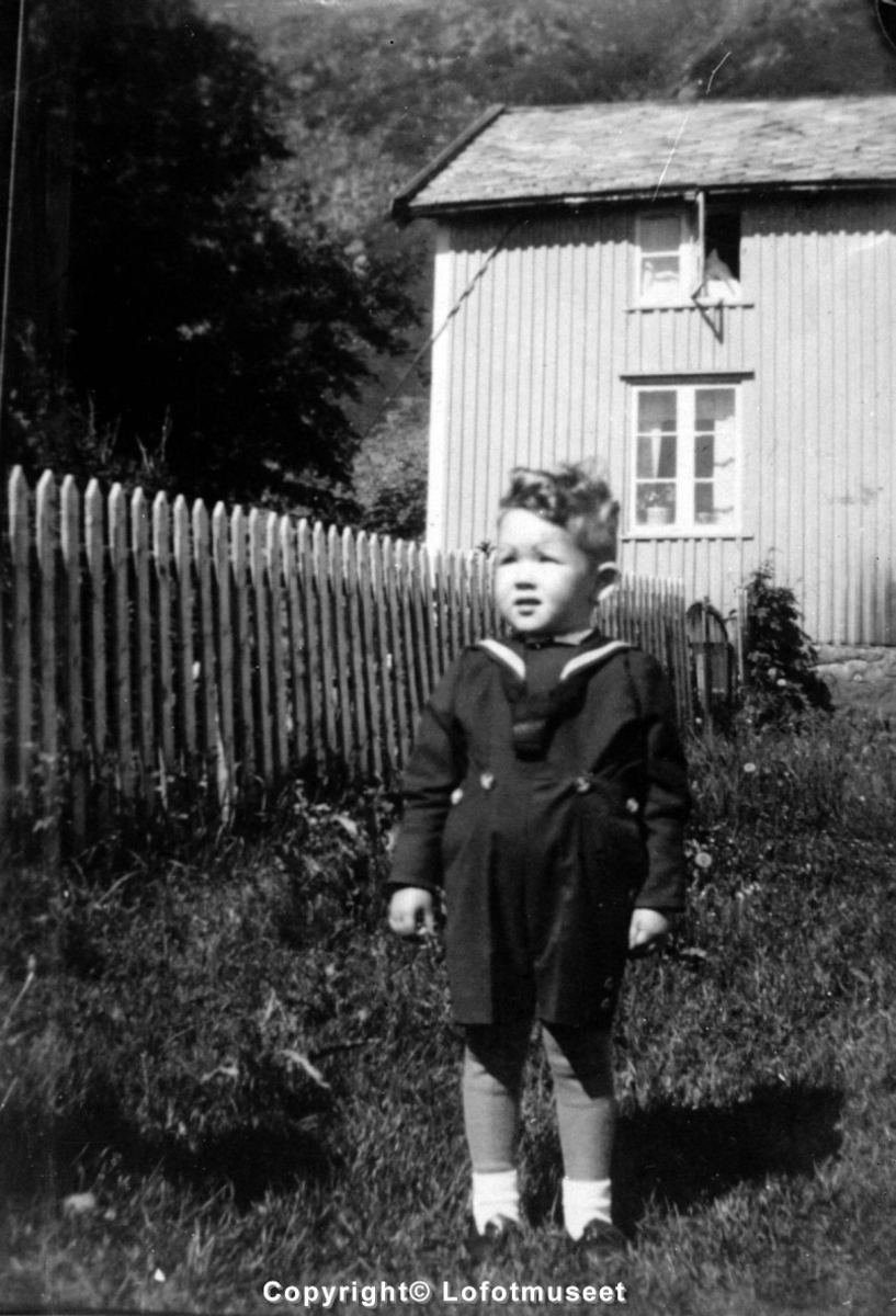 Bildet viser en liten gutt i en hage foran et hus.