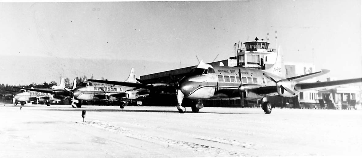 Lufthavn. 3 fly på bakken  De Havilland DH 114 Heron fra Braathens SAFE A/S. Flyet i forgrunnen er LN-PSG "Per". Kontrolltårnet i bakgrunnen
