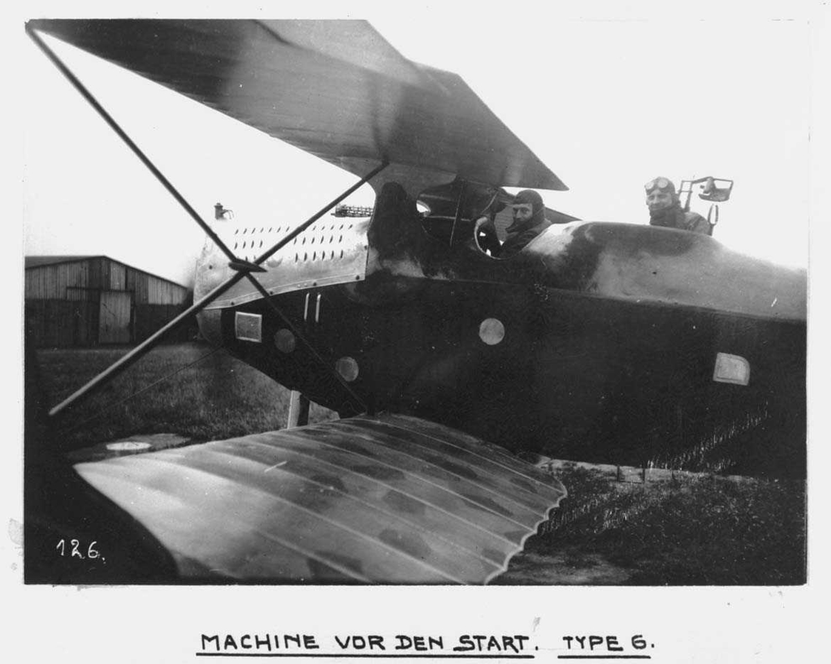 Ett fly på bakken. Hannover C.L.V.TG. To personer, menn i militæruniform, i flyet.