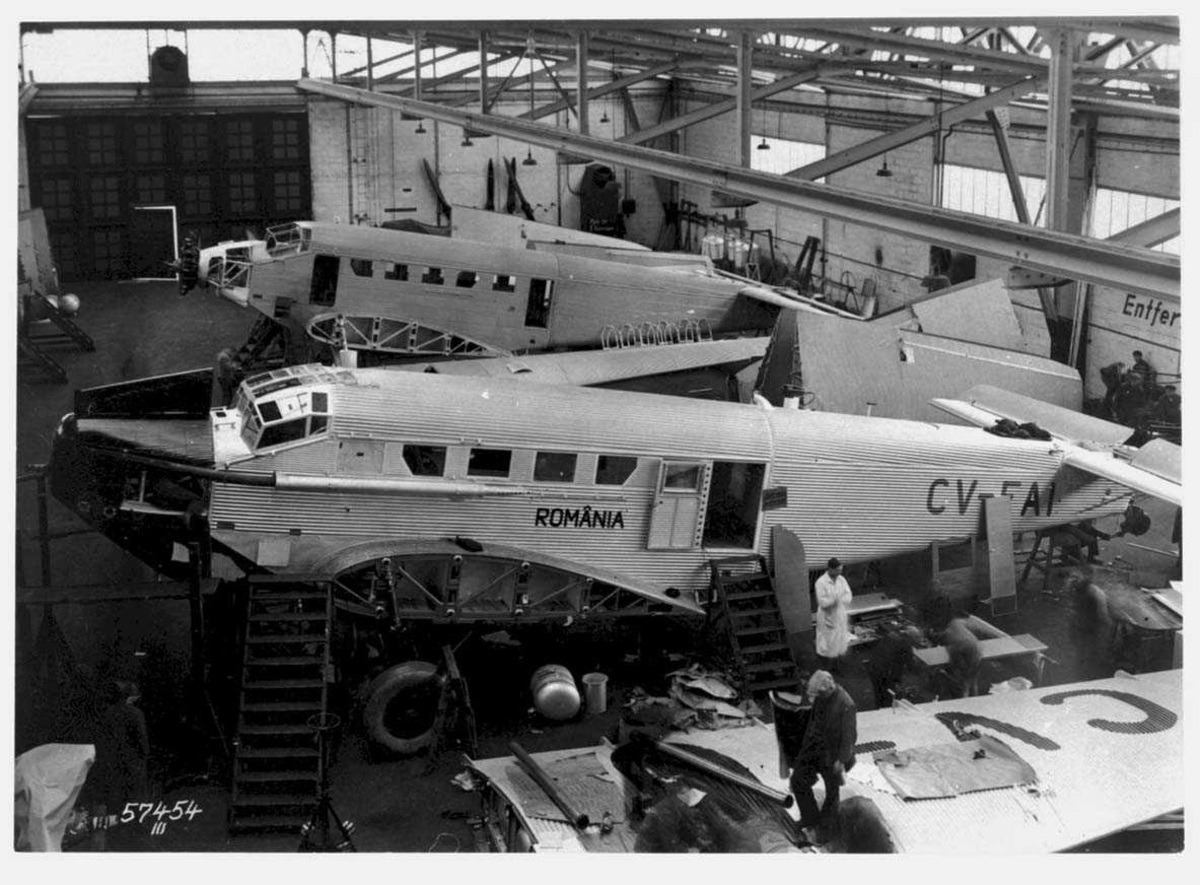 Verksted. Bygging/montering av Junkers Ju52. Noen personer ved flyene.