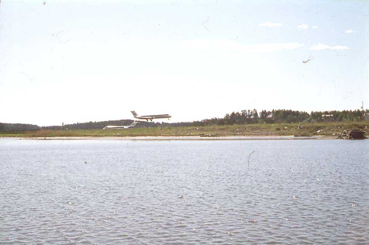 Luftfoto. Ett fly like før landing, McDonnell Douglas DC-9 -21/ -33/ -41 fra SAS. Ett annet på bakken i bakgrunnen.