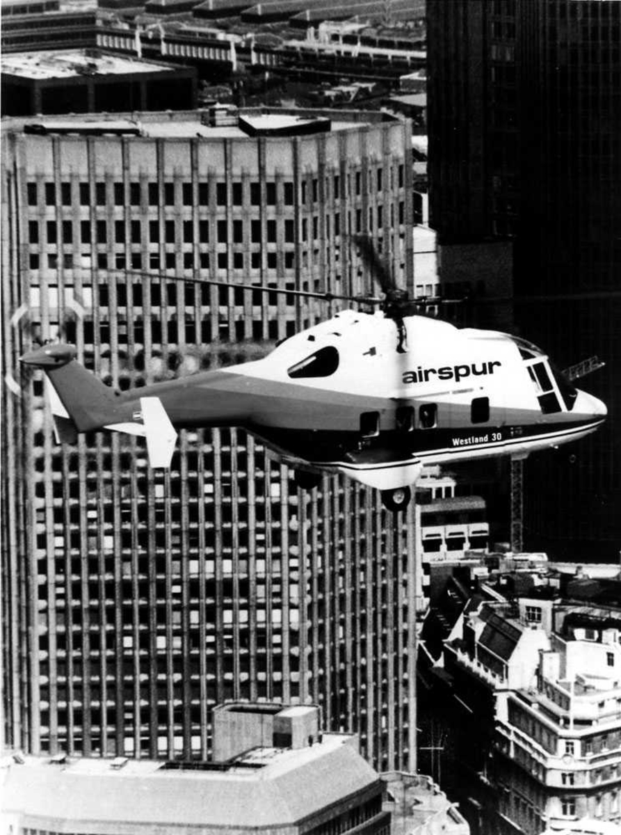 Ett helikopter i luften, over bykjerne. Westland 30 tilhørende Airspur Inc. Skyskrapere 