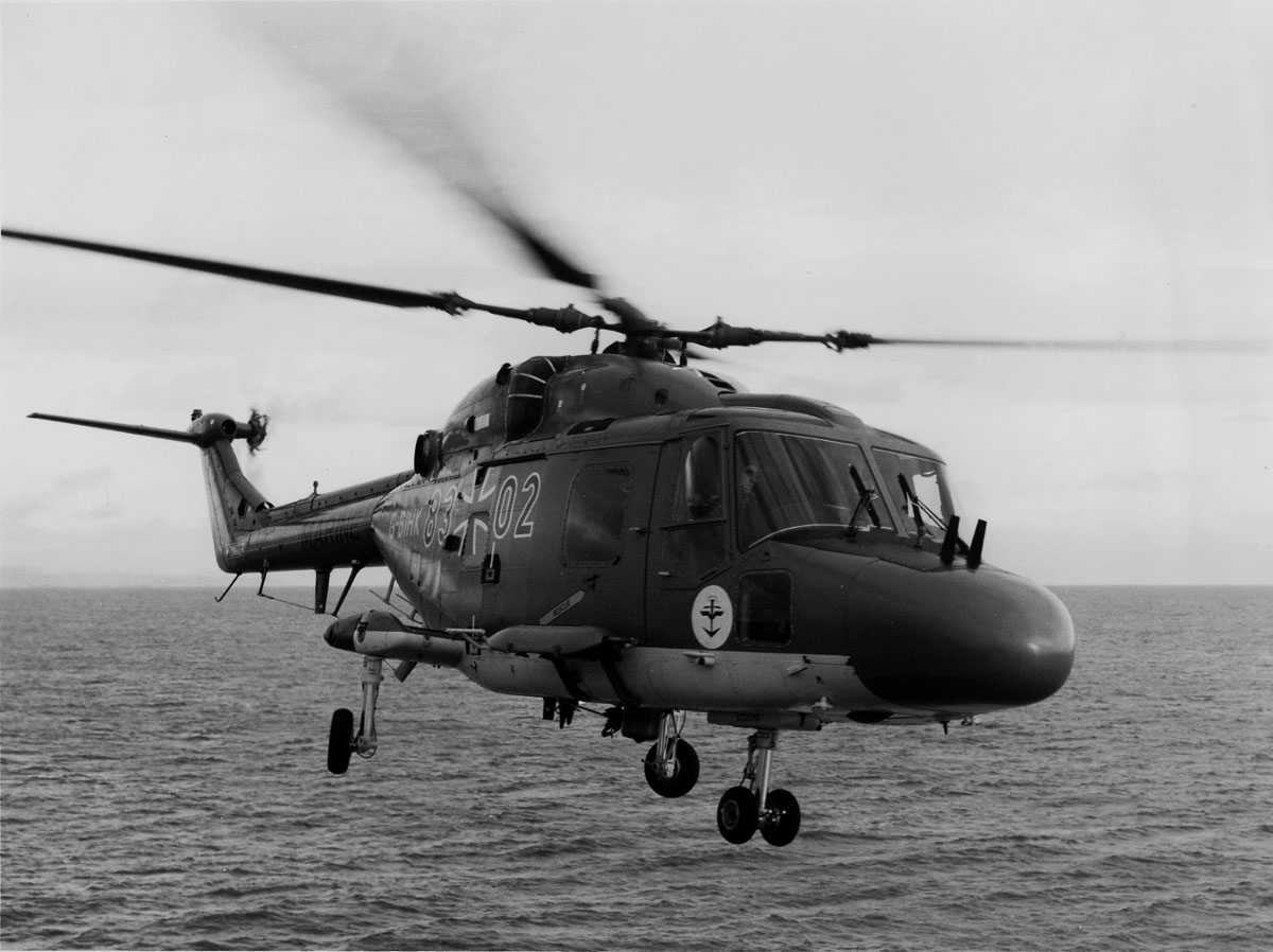 Ett helikopter i luften over sjø. Westland Lynx Mk. 88 tilhørende den tyske marine. Merket Marine G-BIHK 8302