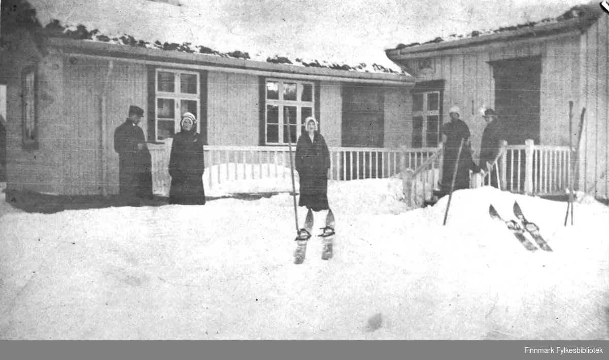 Vinter i Tana. Flere par ski i snøen, og fire kvinner og en mann står utenfor gården Øvre Skoglyst - enten skal de på ski, eller de har nettopp vært ute på tur