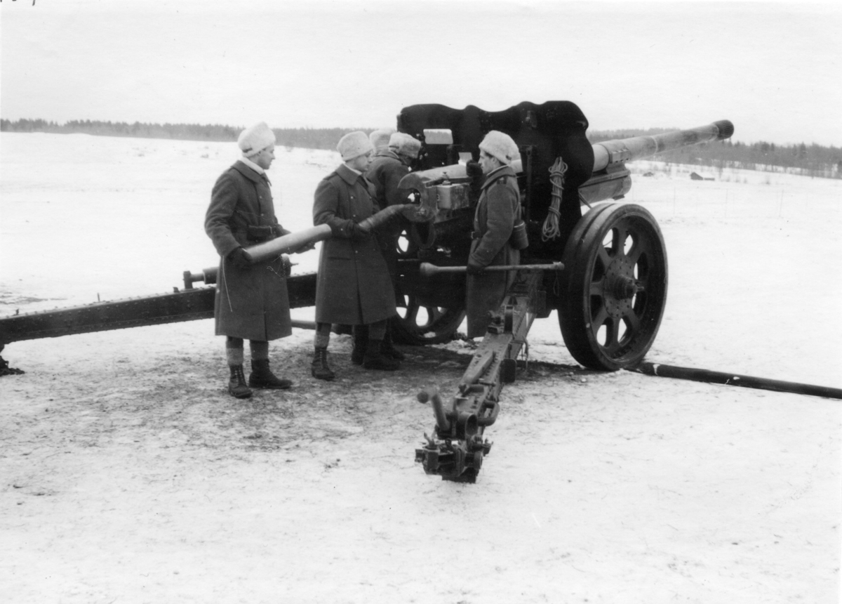 Kanon m/1934. 10,5 cm. A 6, vinter. Vpl laddar kanonen.