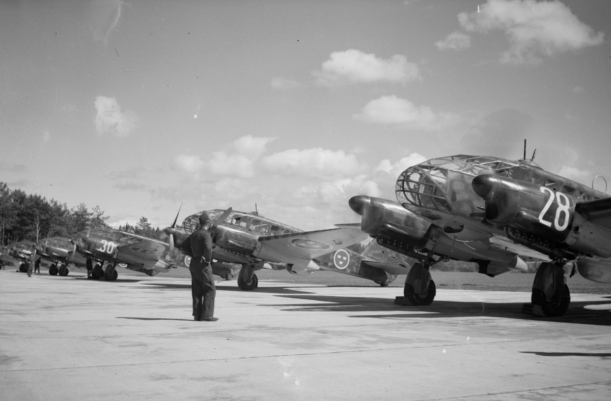 Sex stycken flygplan S 16 Caproni på står på linje på flygfält på F 3 Malmen. Flygplansmekaniker står framför flygplanen. Två av flygplanen märkta med nummer 28, 30.
