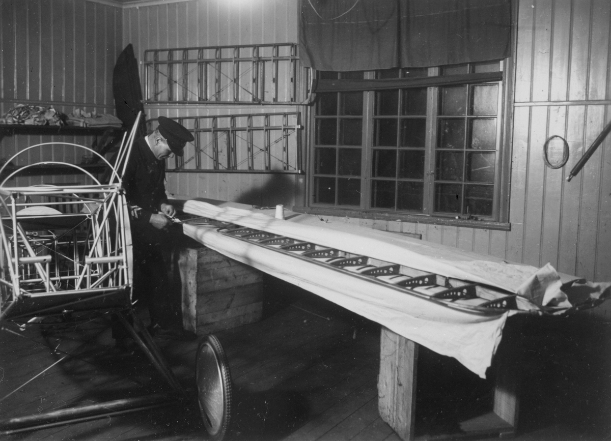 Flygplansbygge. Tyghantverkare George Holmberg i arbete med att klä en flygplansvinge med duk på flygplanet Holmberg Racer.