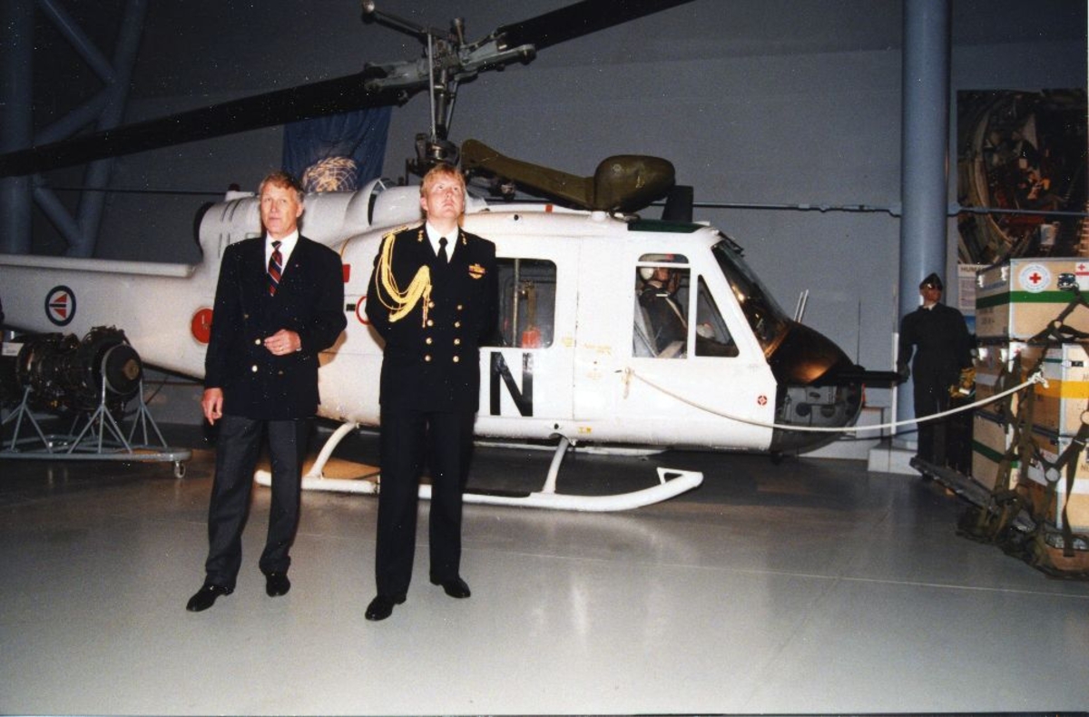 To personer foran ett helikopter: Bell UH-1B Iroquis, amerikansk helikopter.
