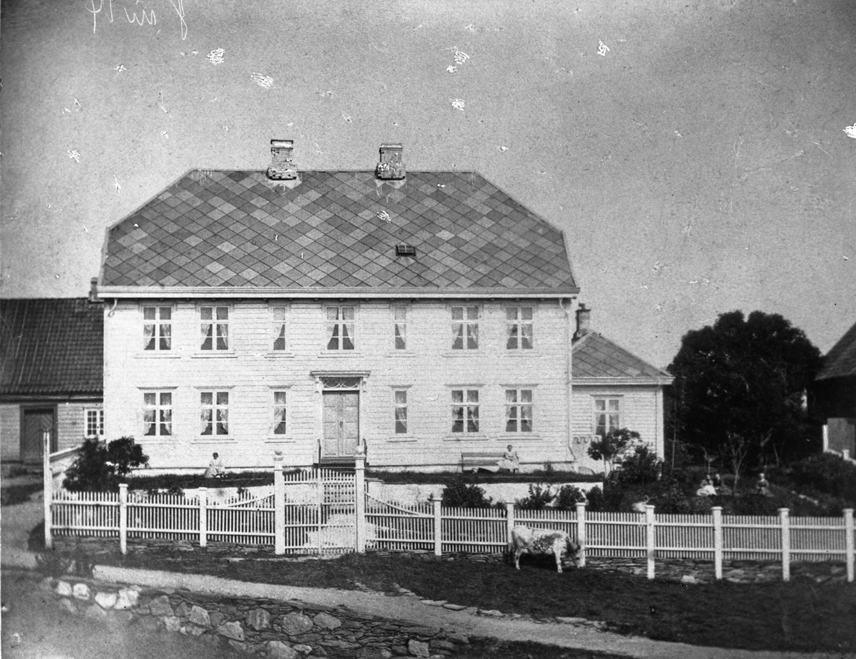 Christiansen-huset i Haugesund, bygget i klassisistisk stil. En gruppe personer sitter under et tre til høyre i bildet.