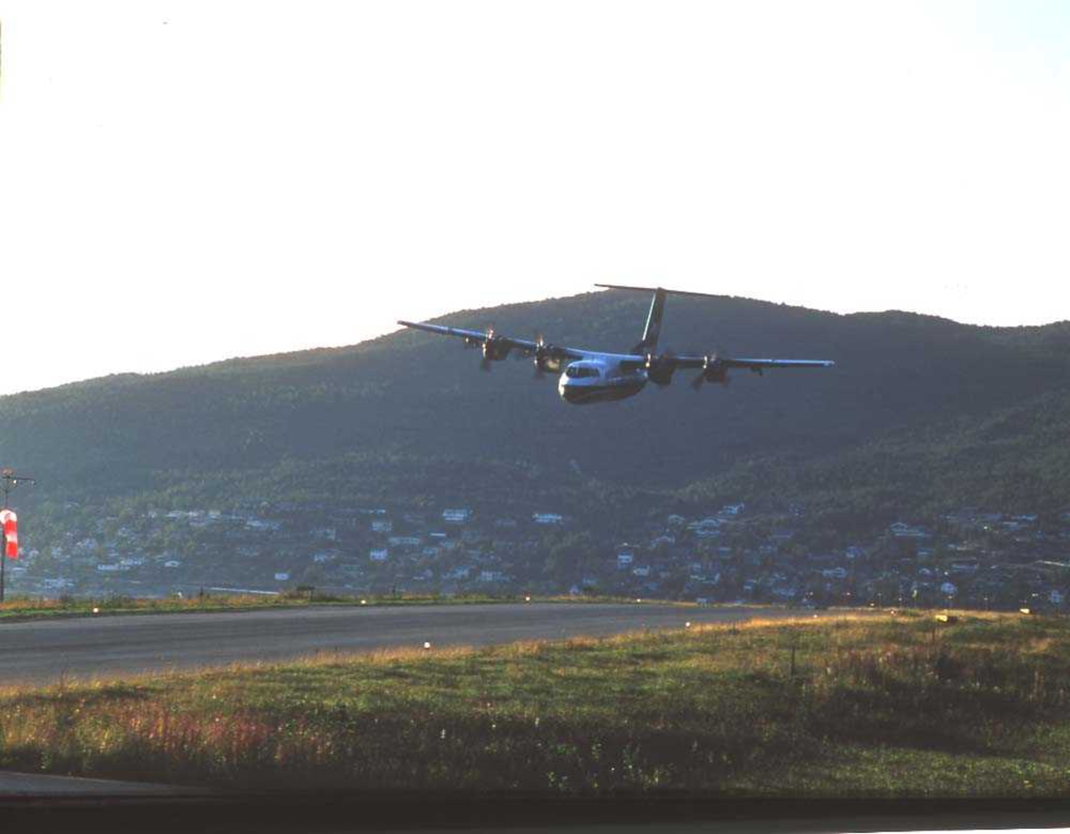 Lufthavn/flyplass. Narvik. Ankenes i bakgrunnen. Ett fly, DHC-7-102/ Dash 7 fra Widerøe, i ferd med å lande runway 03.. 