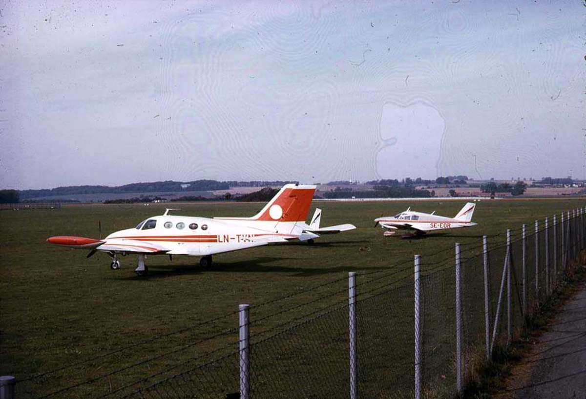 Ett fly på bakken, Cessna 401A LN-TVN. To andre fly i bakgrunnen.