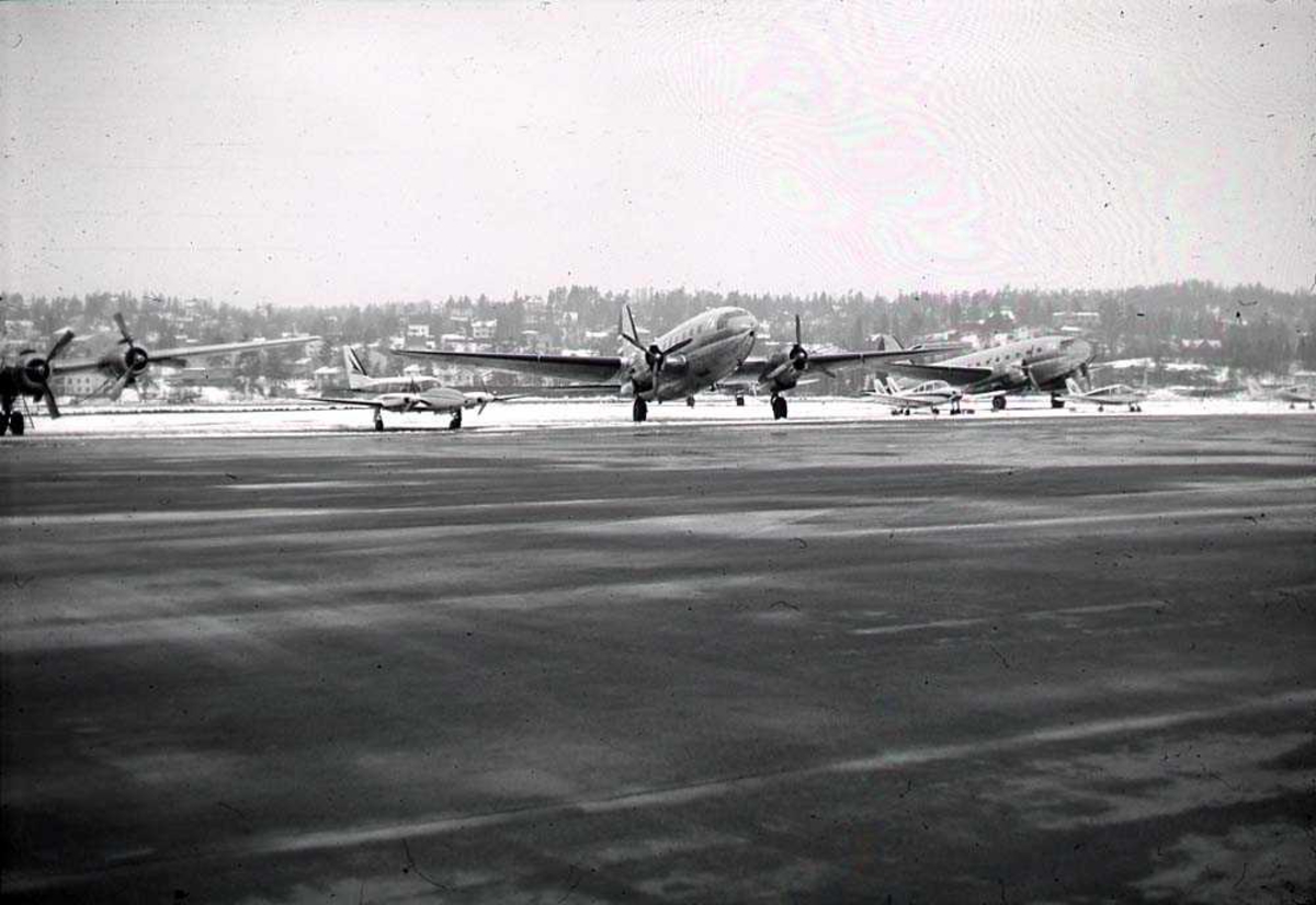 Lufthavn. Ett fly på bakken, Curtiss C-46R Commando fra Fred Olsens Flyveselskap. Flere andre i bakgrunnen.