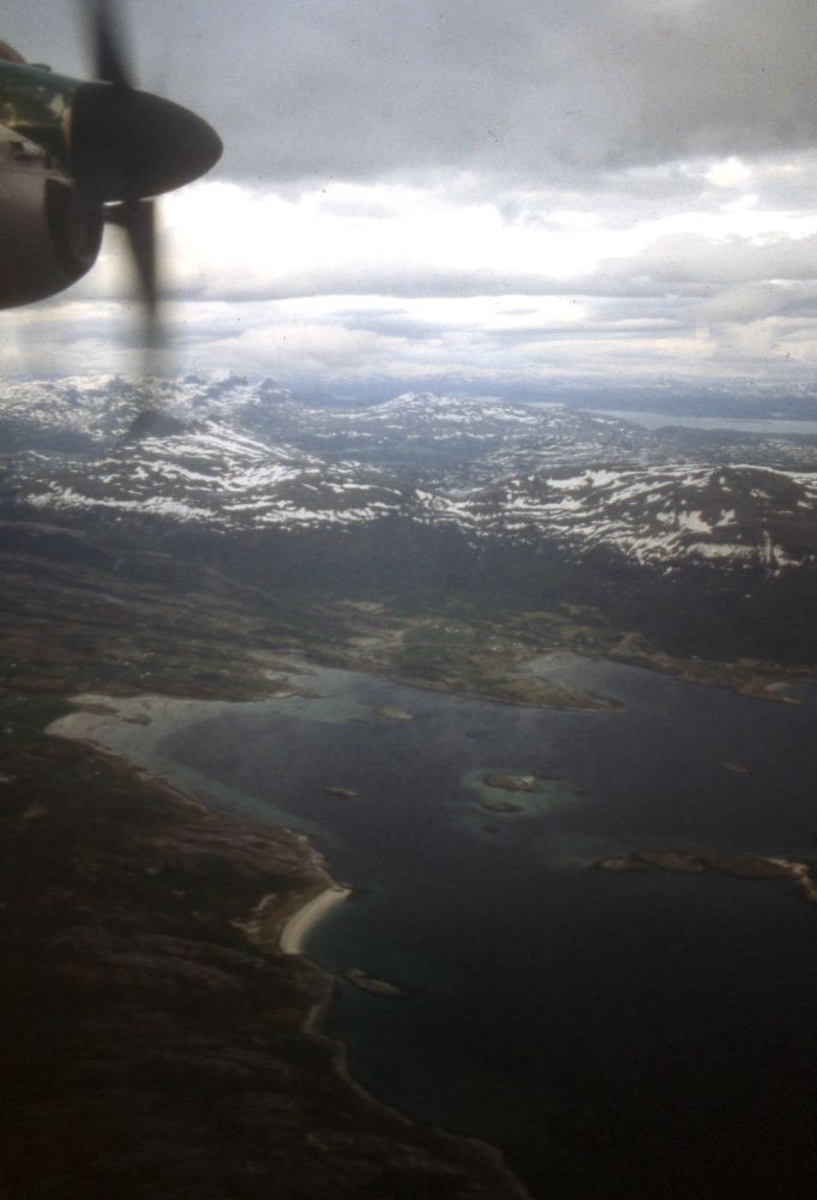 Luftfoto. Et fly, DHC-7-102 Dash 7 fra Widerøe. Fra kabinen ser vi snøkledde fjell.