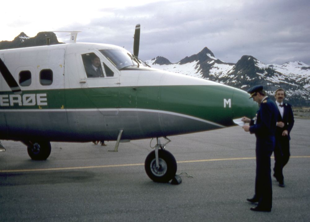 Lufthavn (flyplass). Et fly, LN-BNM, DHC-6-300 Twin Otter fra Widerøe. To personer utenfor flyet, flyger (pilot) og passasjer. I cockpit skimtes en person (pilot).