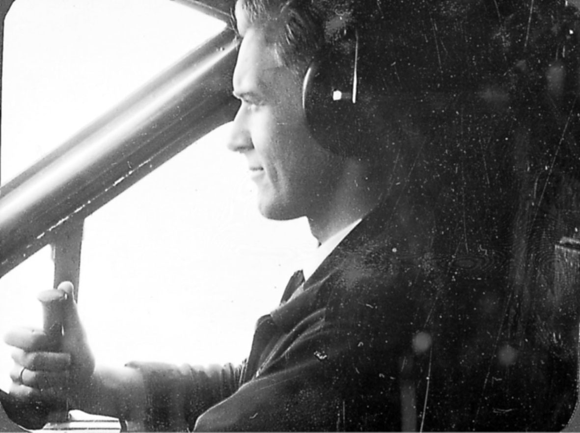 Portrett. 1 person, flyger, sitter i cockpiten på et fly.