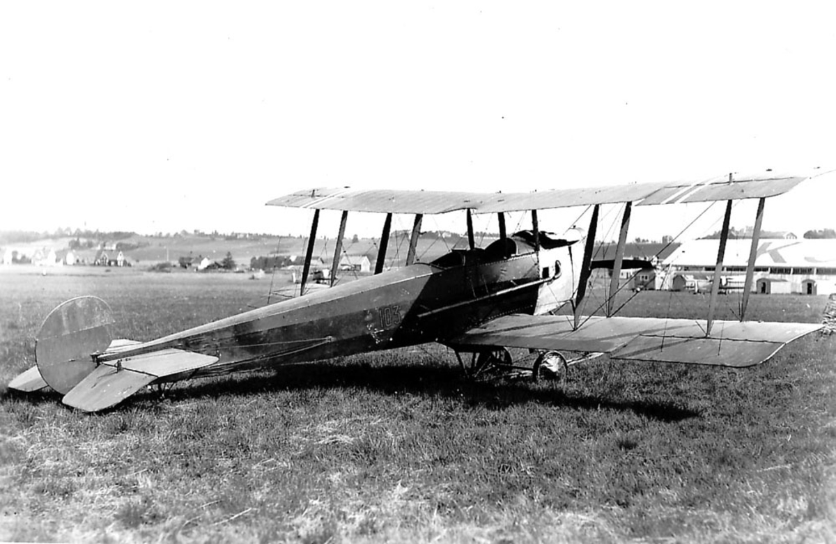 Lufthavn. Ett fly på bakken, Avro 504, Nr. 103. to andre fly og flere bygninger i bakgrunnen.  Kjeller.