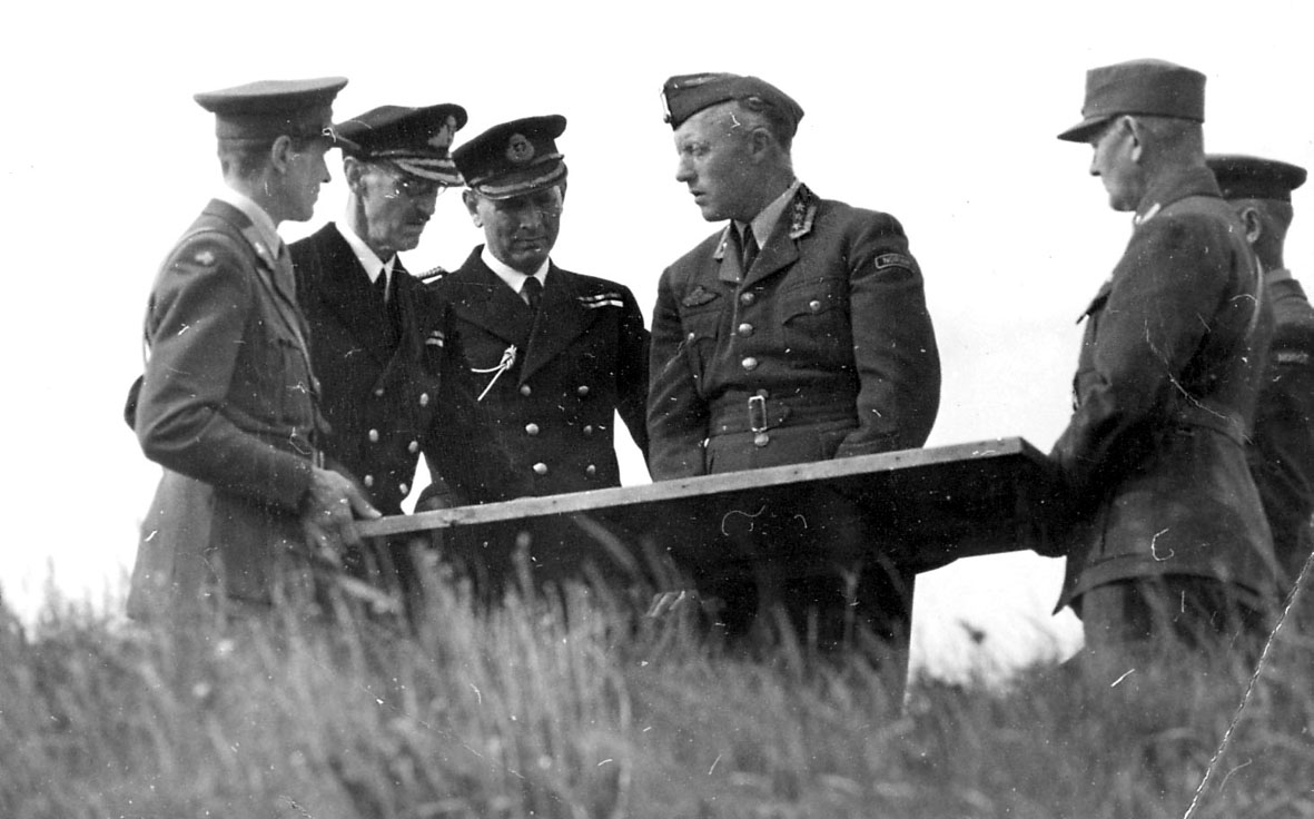 Gruppefoto, fem personer, kong Haakon og oberst Ole Reistad +
tre offiserer.   