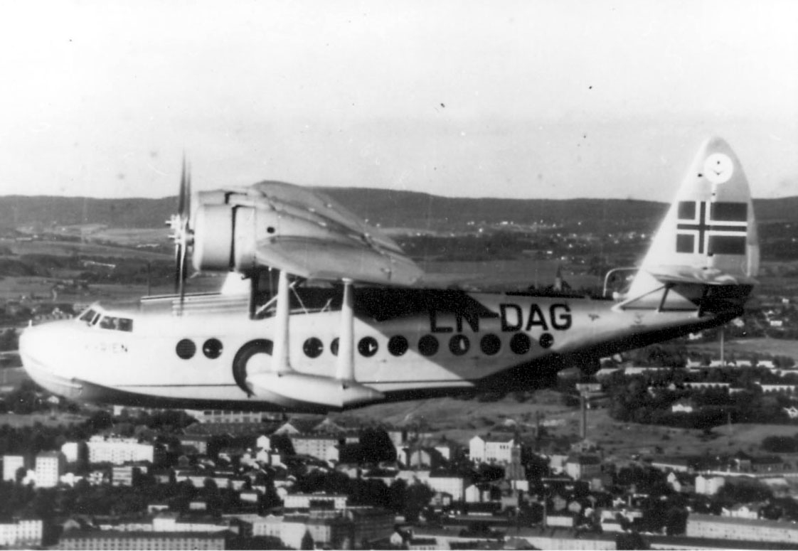 Luftfoto. ett fly i luften, Sikorsky S.43, LN-DAG, "Valkyrien".  Bebyggelse, tettsted  sees under.