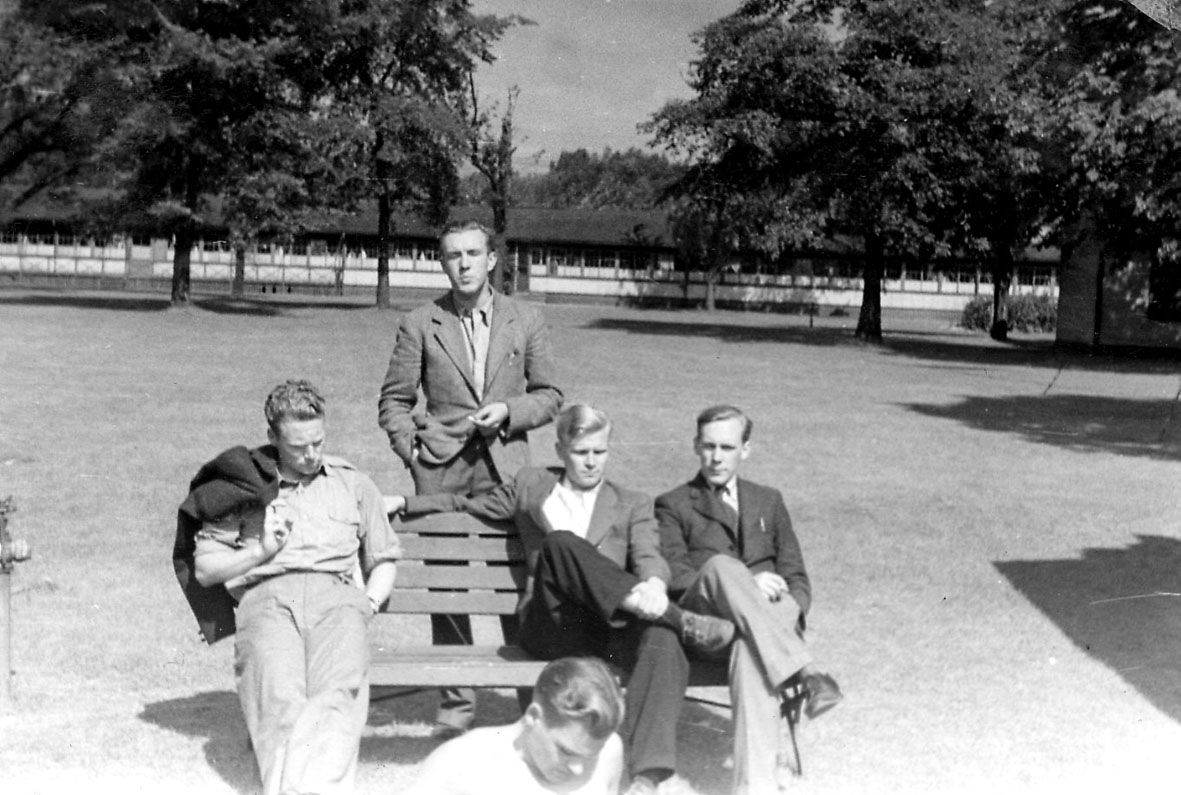 Portrett, fem personer ved en benk i en park. 