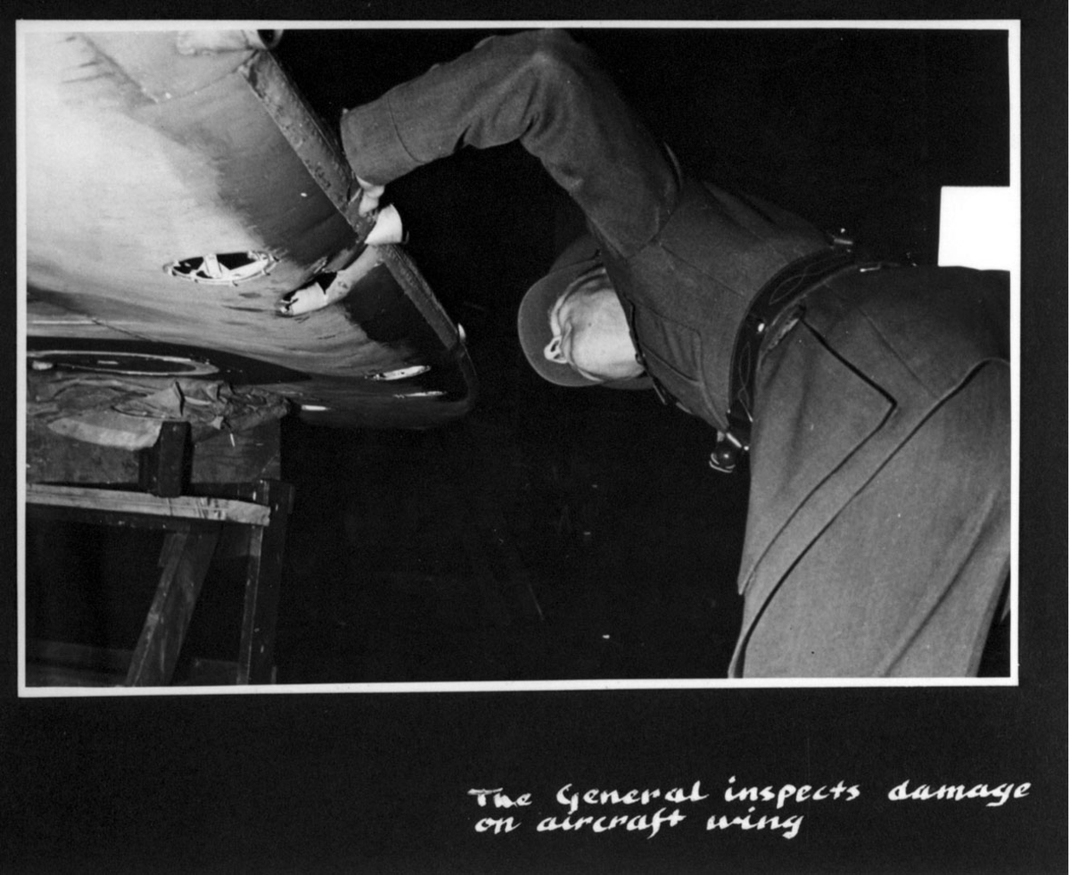 Person i militæruniform, studerer skadet vinge på et fly. (Ant. General W. Hansteen).