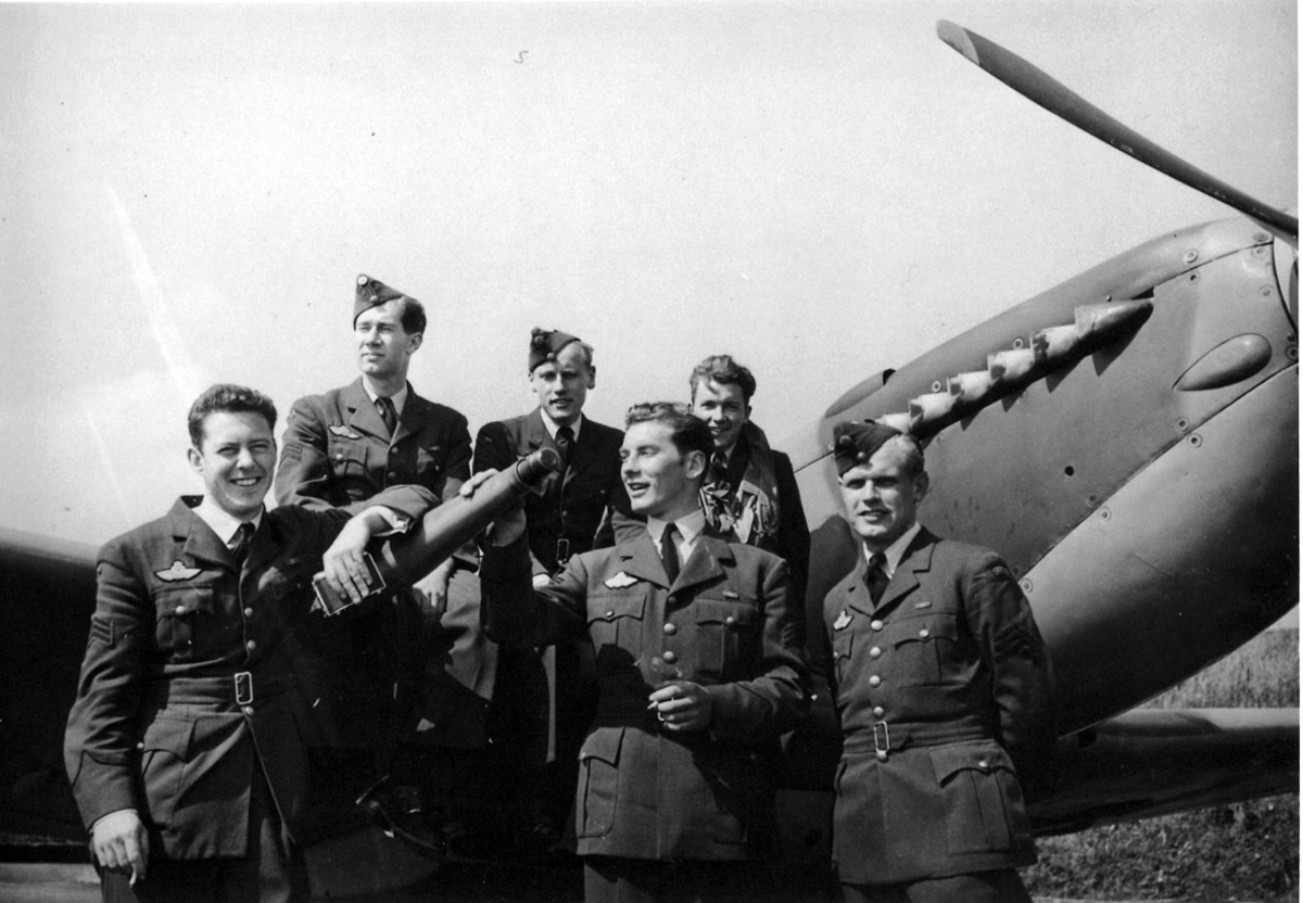 6 personer i militæruniform foran fly, Spitfire.