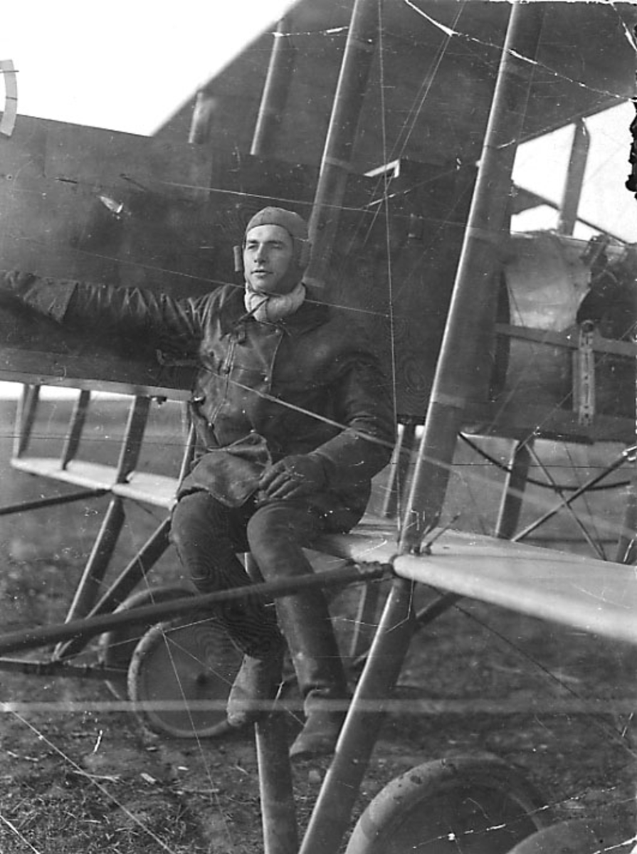 1 fly på bakken, Morris Farman, midtpartiet og ene vingen sett fra siden. 1 person sitter på vingen, pilot.