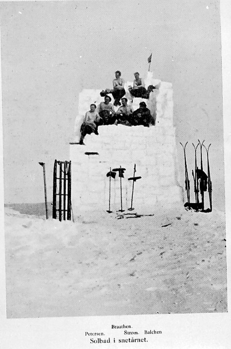 Portrett, flere personer sitter i et "tårn" konstruert av snøblokker. Skiutstyr og 1 kjelke står bå bakken under tårnet. Tatt utendørs. Snø på bakken.