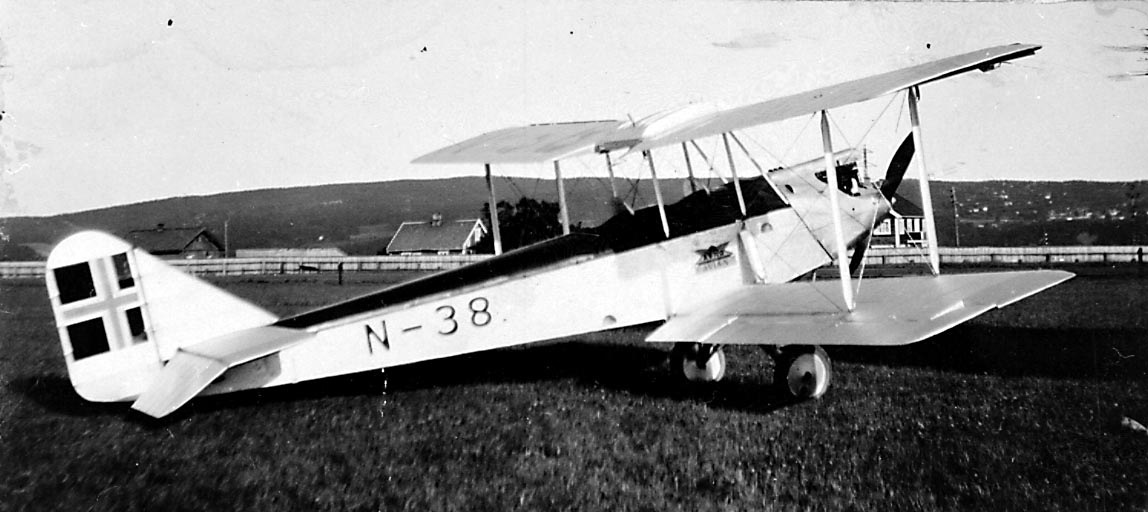 1 fly på bakken, Avro 594 Avian IV, N.38 LN-ABF fra A/S Norsk Lufttransport.  Bygninger i bakgrunnen.