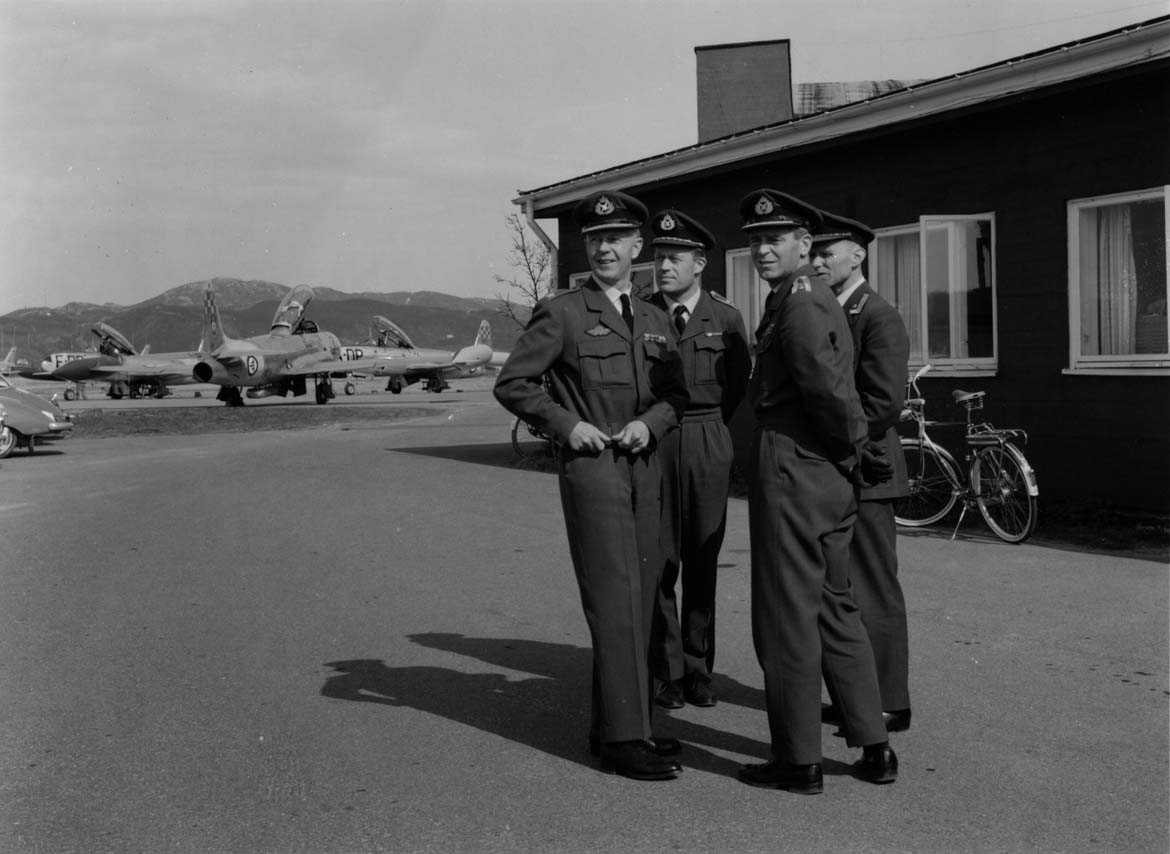Gruppe  Fire personer i uniform flere fly i bakgr. T-33.