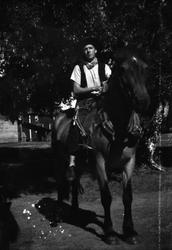 Roar Jøraholmen iført cowboyhatt rir på en hest om sommeren,