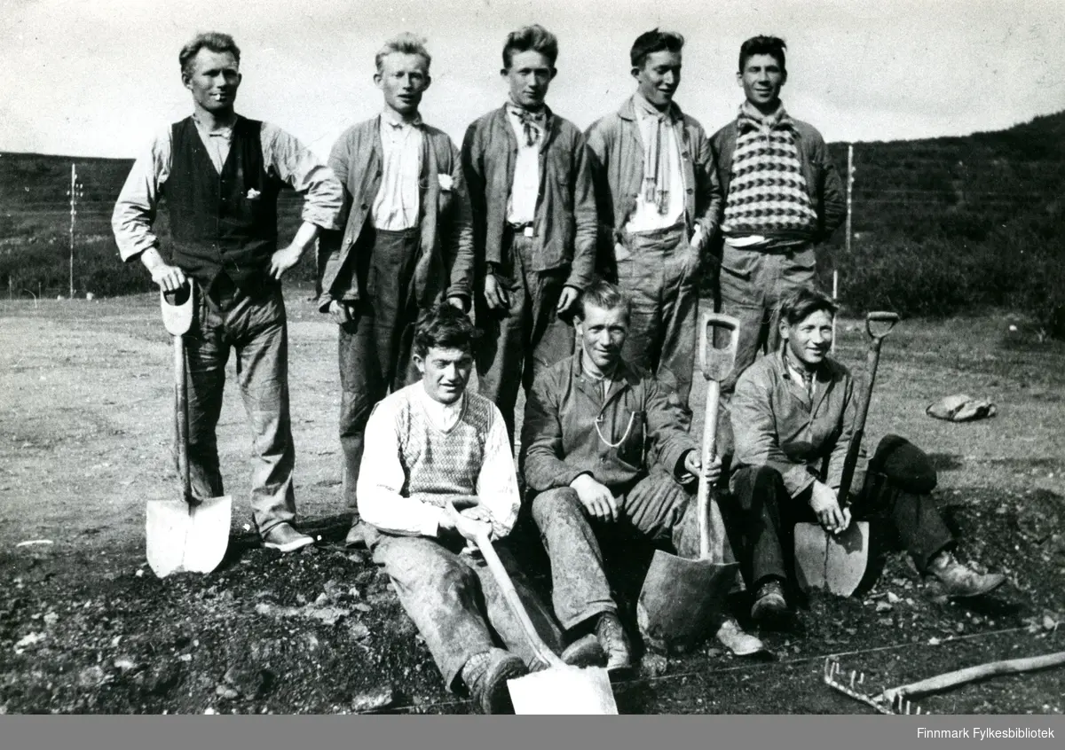 Bildet viser åtte unge menn, poserende med spader. Stedet er Oterbekken i Nesseby antakelig rundt 1935.