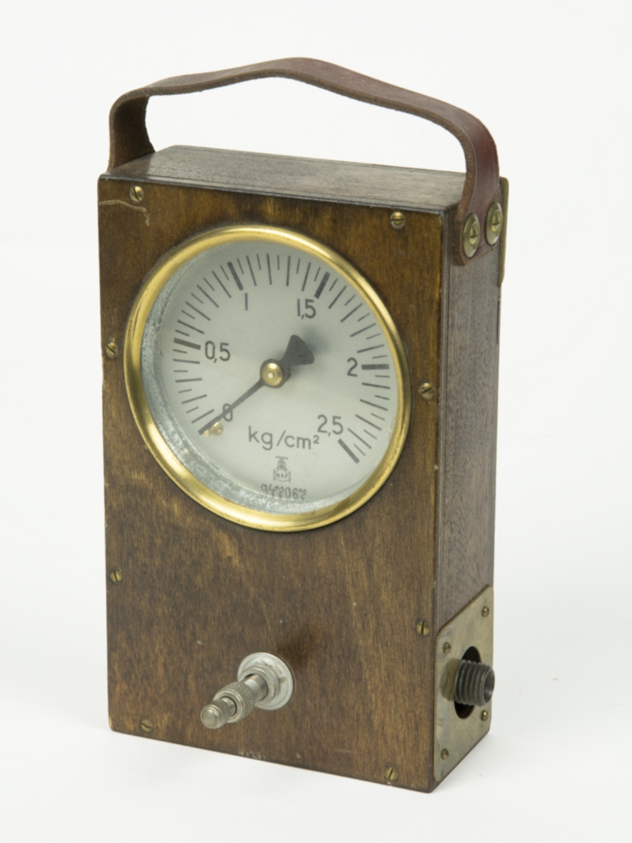 Kontrollmanometer, möjligen för lufttryck. Graderad 0-2,5 kg/cm2. Har ett bärhandtag i läder.