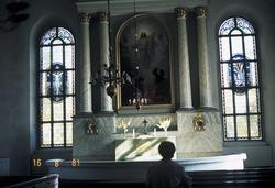 Aase Jacobsen på en kirkebenk i Finland. To gotiske vinduer 