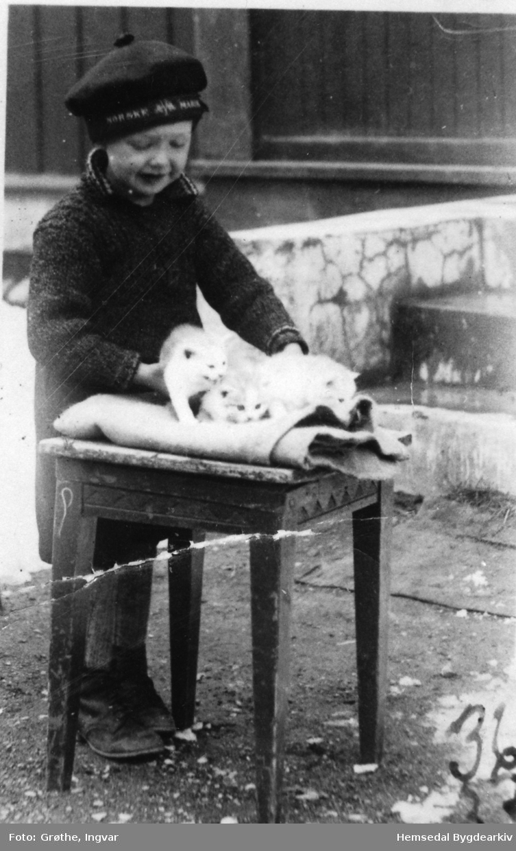 Johnny Grøthe steller ut kattungar utanfor barndomsheimen sin, Fagerheim, 67.37, i Hemsedal i 1936