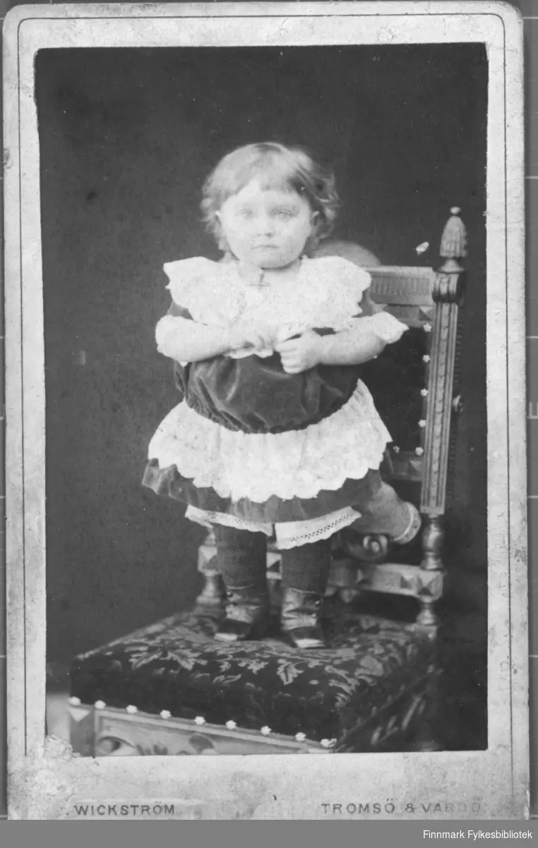 Portrett av barn jente i kjole hun står på en stol. ateliere studio fjeset hennes er uskarpt Albumet med bildet kommer fra Ekkerøy, kanskje han kommer derfra.