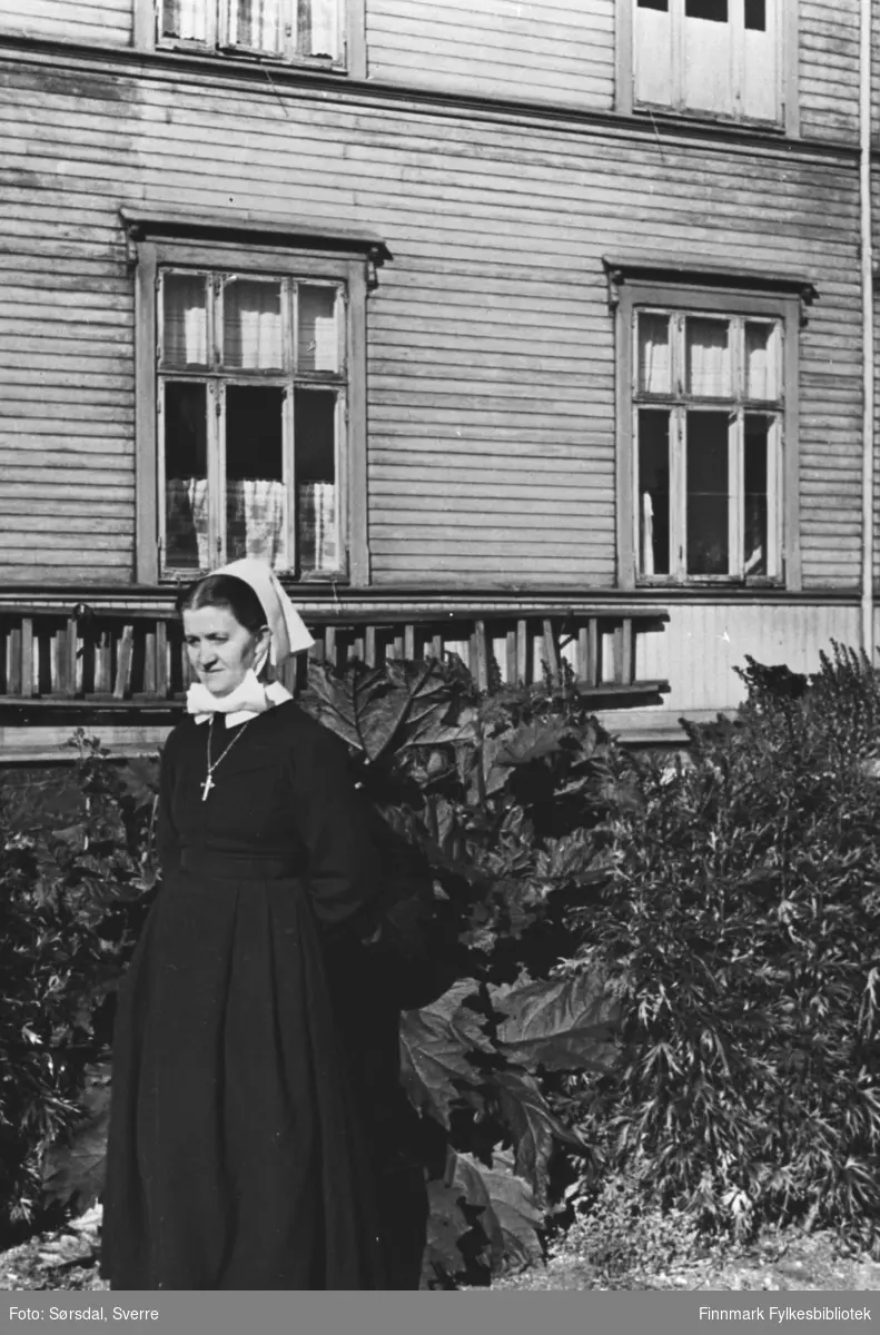 Bildet av oversøster Martha Eckmann i uniform. Står ute foran Vardø sykehus.