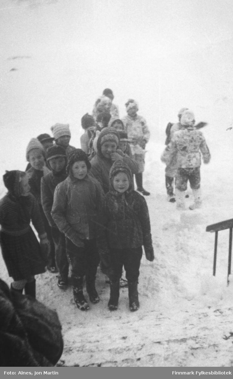 Elevene tar oppstilling foran inngangen til Øksfjord barneskole en vinterdag i 1954. Noen har tydelig lekt en del i snøen før skoledagen skal begynne