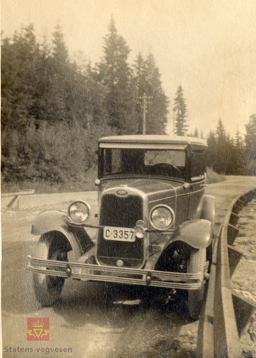 Dette er en 1928 modell National series AB med kjennetegn C-3357. Siste år med 4 cyl.motor.  Endret radiatorkappe og lenger panser enn i 1927. Det var forberedelse til den 6 cyl. motoren som kom i 1929. Bilen er parkert ved et rekkverk som er konstruert av Nikolai O. Saxegaard. "Fig. Skrårekkverk fra Akershus fylke." Bildet viser hvordan rekkverket var konstruert for at man kunne kjøre helt inntil uten å skade kjøretøyet. På den måten fikk man benyttet hele kjørebredden på smale veger ved møtende trafikk.  Saxegaards bilvennlige rekkverk er omtalt i  "Våre veger, Bd 6, nr.3, april 1980, side 46." Saxegaard skrev også en artikkel i "Meddelelser fra Veidirektøren", Nr. 8-August 1930, side 121, "Veirekkverk i Akershus fylke og nogen ord om rekkverk-spørsmålet i det hele." Se vedlegg. 

Opplysninger til kjøretøyet på bildet v/tidligere daglig leder John Hindklev ved Norsk Kjøretøyhistorisk Museum.
04.04.2016: "Bilmerket er Chevrolet, kfr. den kjente logoen inne i ovalen øverst på radiatorkappa. Chevrolets ga noen år til og med 1932 et eget navn til de enkelte årsmodeller, som National i 1928 og International i 1929."
04.04.2016: "C-3357 står i Bilboken for Norge 1930 på ingeniør J. Voss, Grefsen. Kanskje ansatt i Veivesenet?" Opplysninger til kjøretøyet på bildet  v/ Ivar Erlend Stav.