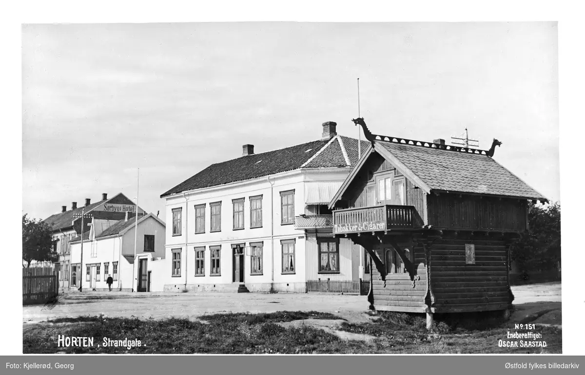 Horten i Vestfold med parti fra Strandveien. Til høyre stabbur i dragestil, påmalt tekst: "Tobakker og Cigarer". Lengst til venstre Sørbye's Hotel.