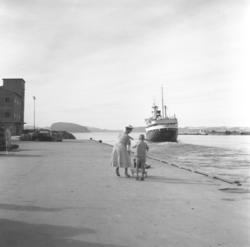 En kvinne og et barn står på Dampskipskai og ser at Hurtigru