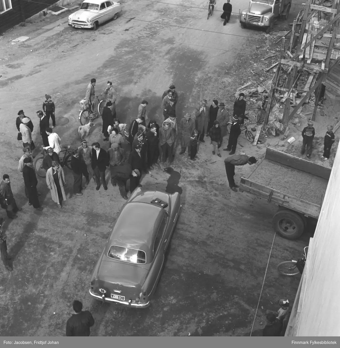 Fotografi tatt fra Televerkets nybygg i krysset Storgata/Sørøygata. I forgrunnen, ovenifra: En Opel Rekord 1953-34 med registreringsnummer Y-130. I bakgrunnen fra venstre: Opel Kaptein årsmodell 1954-55 og en Volvo lastebil.