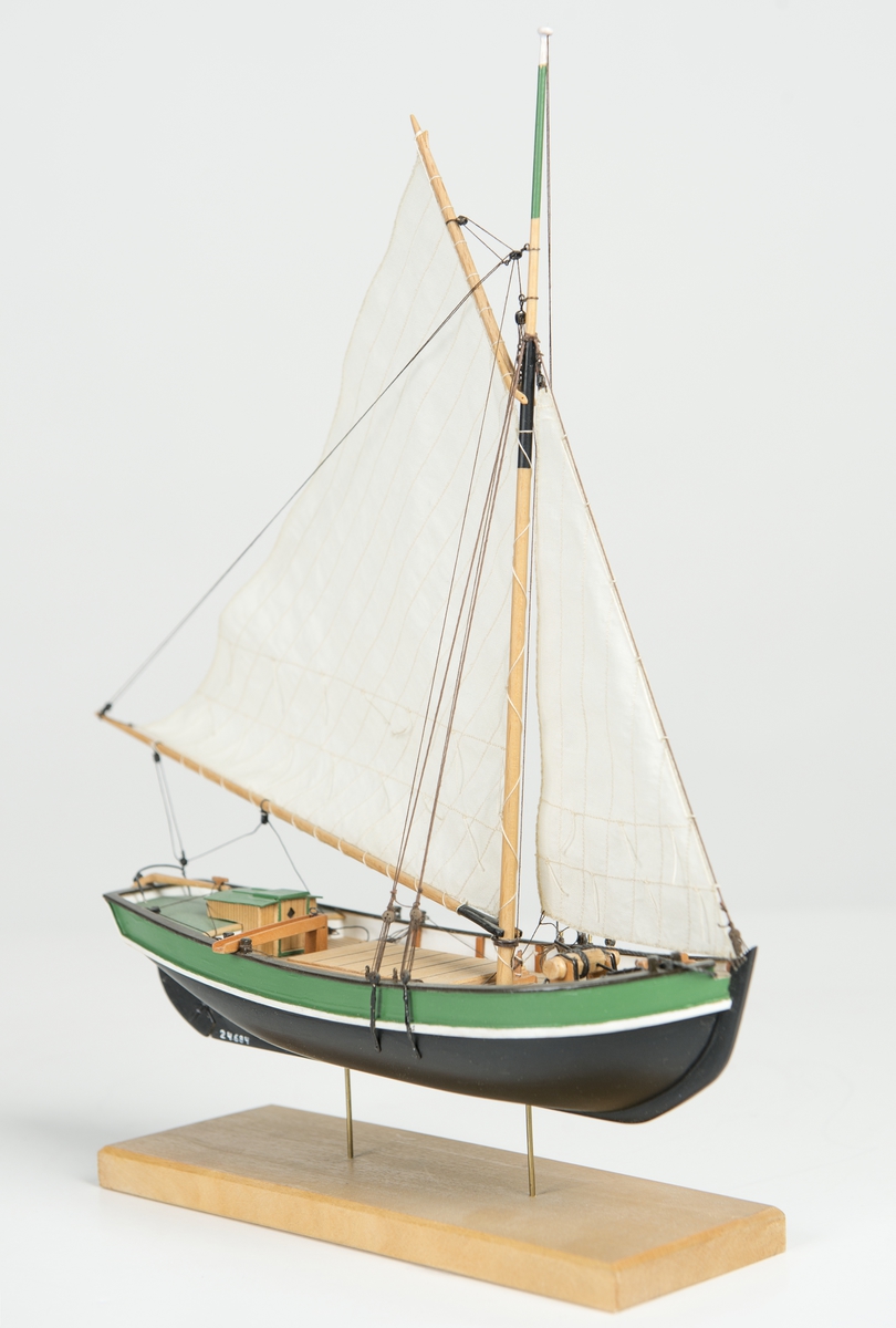 Riggad med fock och gaffelstorsegel. Svart skrov, grön bredgång. Vit kaltopp. Modellen tillverkad till utställningen "Seglande kungar, kungliga seglare", KSSS 150-årsjubileum 1980.