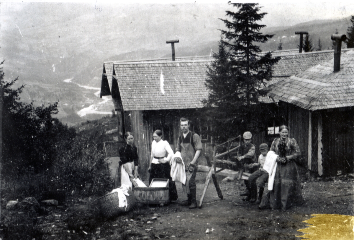 Mennesker ved badehuset og vaskeriet på Breidablikk Sanatorium. Kvinner med vaskebalje og vaskebrett. Syver Framnes midt i bildet, og Kristine Hagene (Gimle) helt til høyre