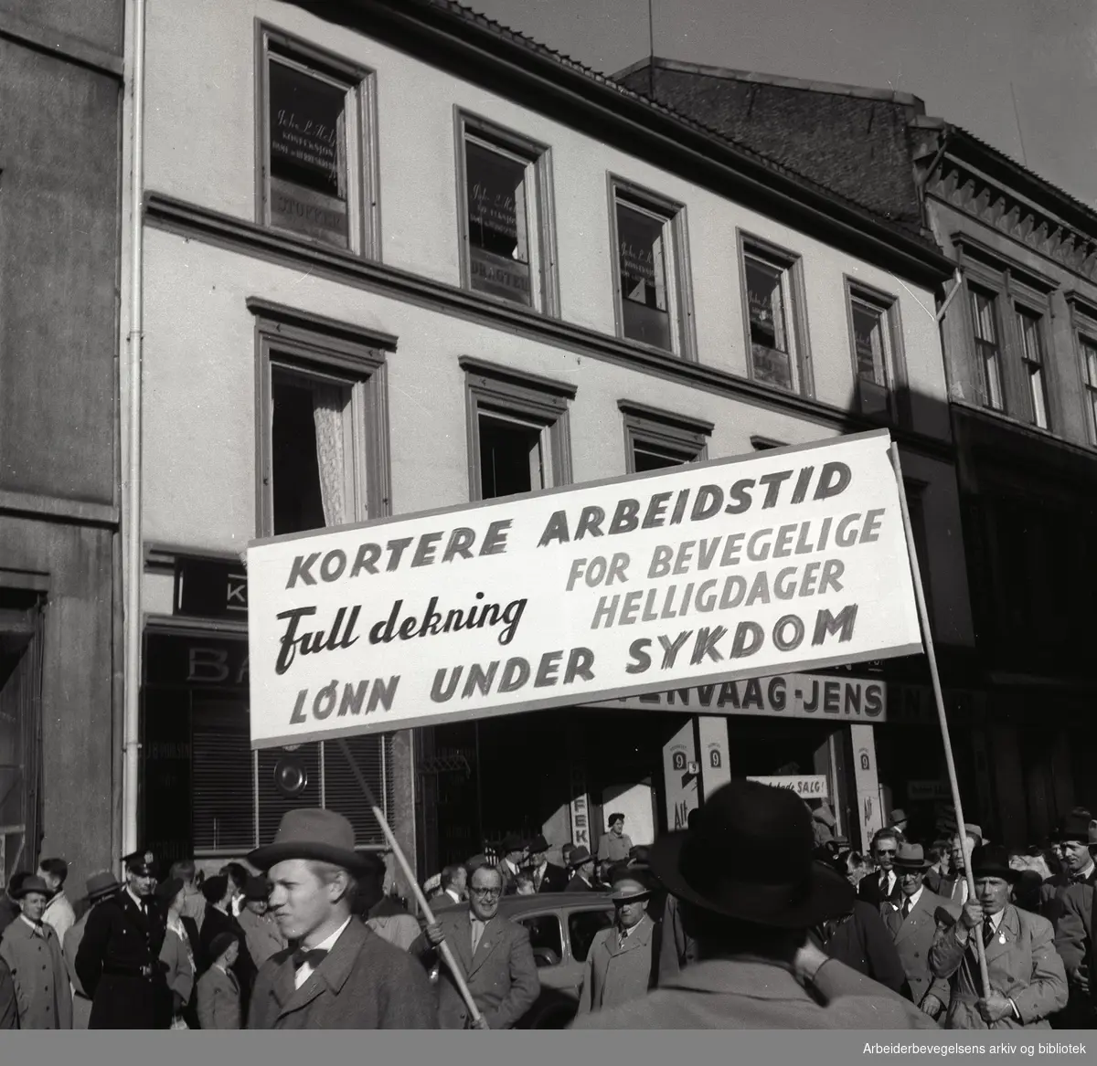 1. mai 1956, demonstrasjonstoget på Youngstorget. Parole: Kortere arbeidstid. Full dekning for bevegelige helligdager. Lønn under sykdom.
