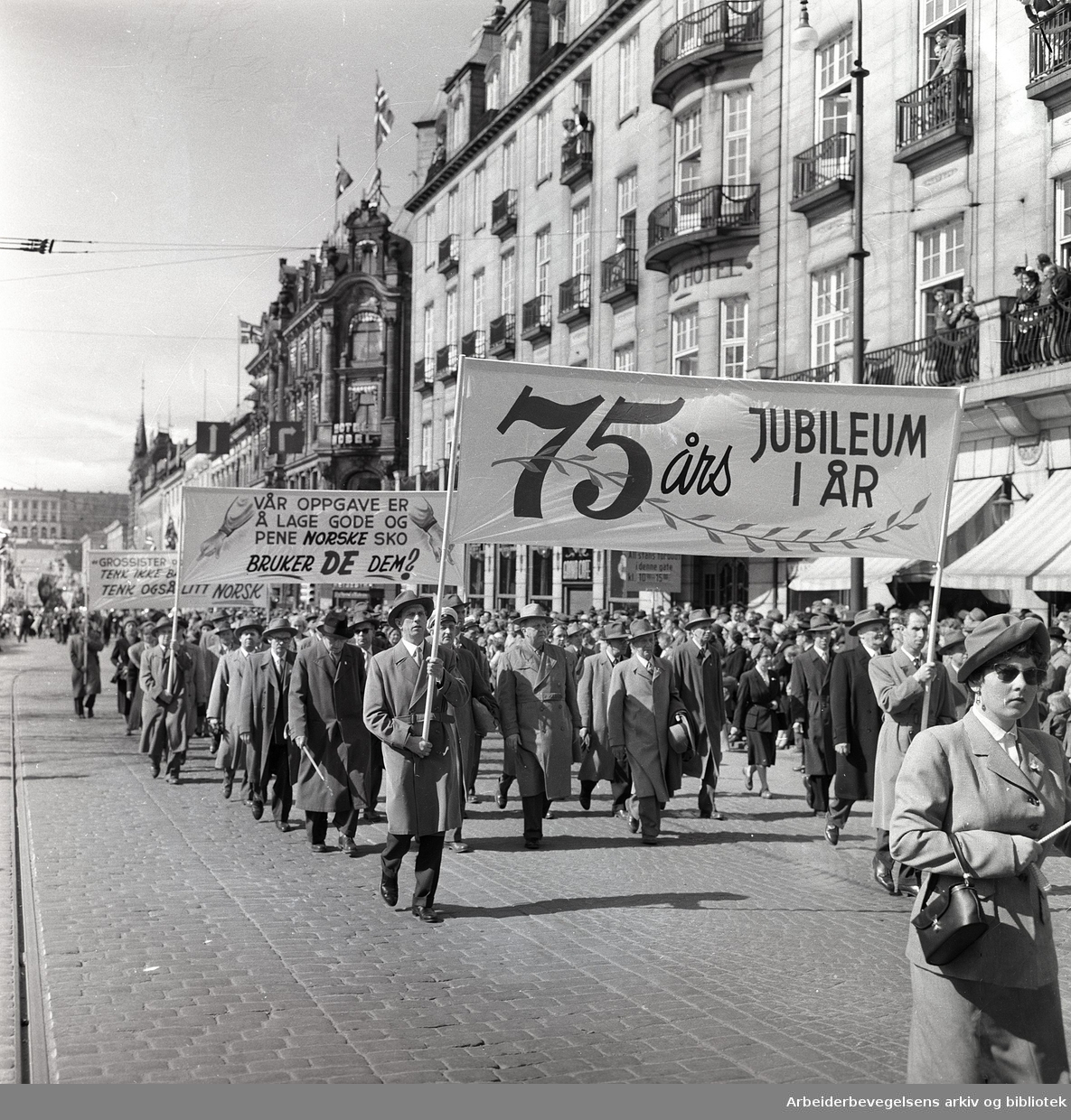 1. mai 1958 i Oslo.Demonstrasjonstoget på Karl Johans gate.Parole: 75-års jubileum i år.Parole: Vår oppgave er å lage gode og pene sko. Bruker DE dem?.