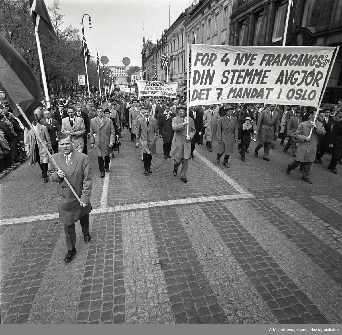 1. mai 1961 i Oslo.Demonstrasjonstoget i Karl Johans gate..Parole: For 4 nye framgangsår.Din stemme avgjør det 7. mandat i Oslo.Parole: Demokrati i arbeidslivet = industrielt demokrati.