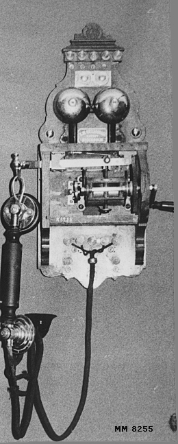 Väggtelefon av mindre modell troligen från slutet av 1800-talet eller början av 1900-talet. Innesluten i en kåpa av mahogny. Kåpan trasig.
Märkt: "L.M. Ericsson & Co Patent Stockholm".