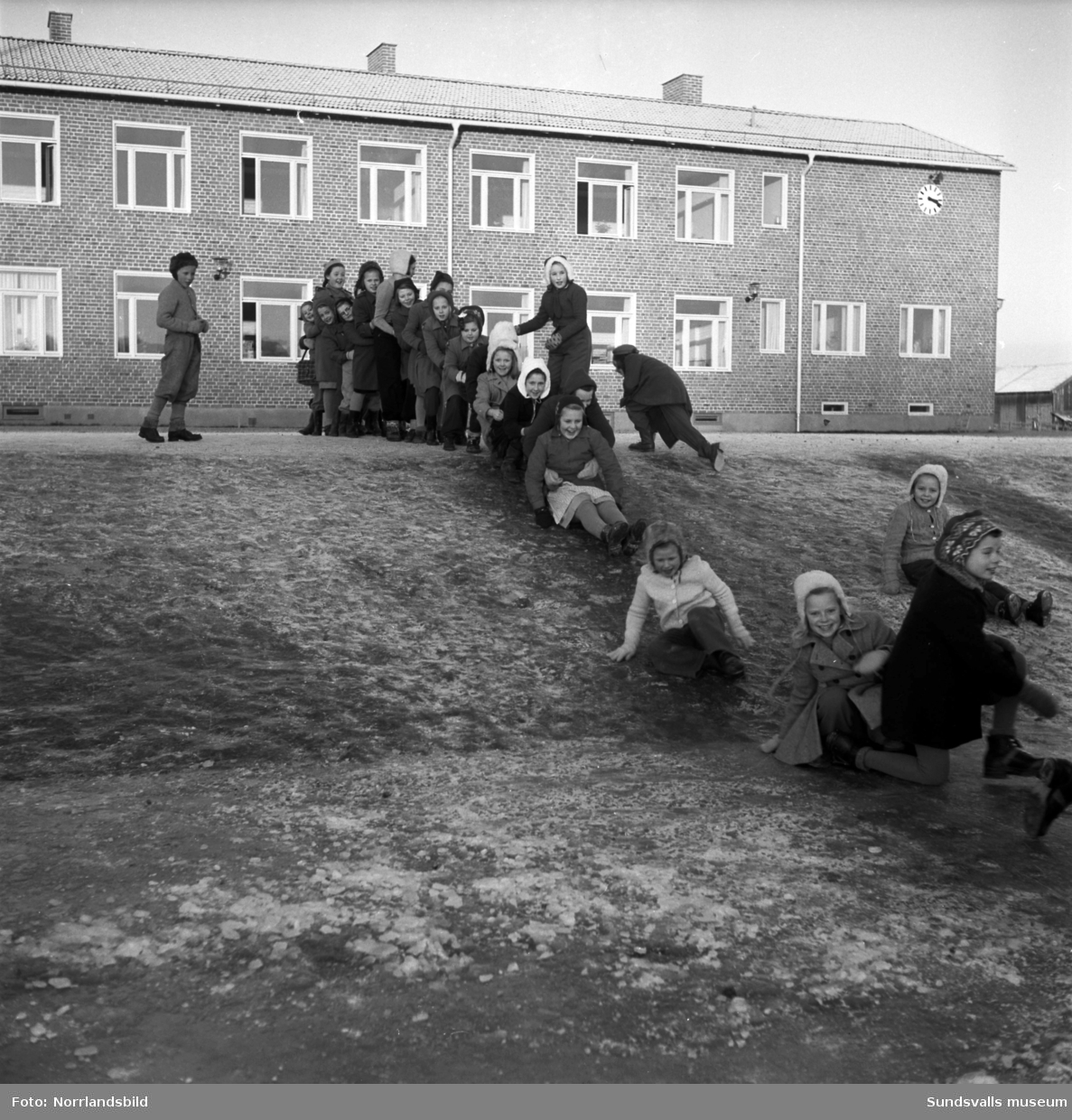 Reportagebilder från Stöde skola 1950. Exteriör, interiör, lektioner i klassrummen, rastlek, elever, personal, lärarrum, affischförråd samt en del andra hus i omgivningen.